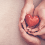 mani che tengono un cuore rosso per sensibilizzare al controllo del colesterolo e alla salute cardiovascolare