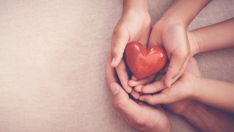 mani che tengono un cuore rosso per sensibilizzare al controllo del colesterolo e alla salute cardiovascolare